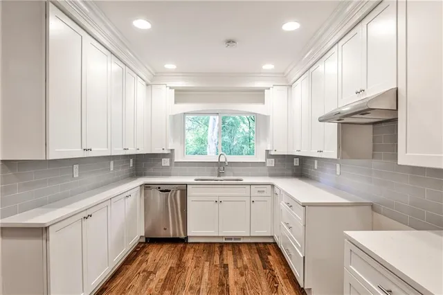 a kitchen with a sink dishwasher a stove a refrigerator and cabinets with wooden floor