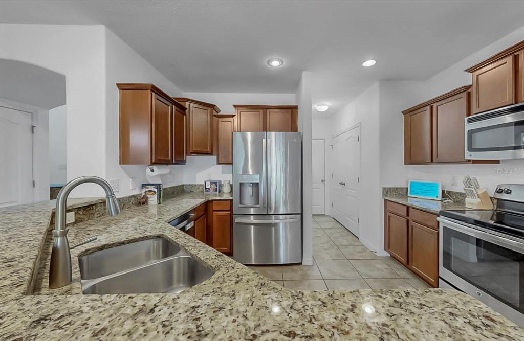 10012 Newminster Loop Ruskin, FL 33573 - Photo 13 of 59 a kitchen with stainless steel appliances granite countertop a sink stove and refrigerator