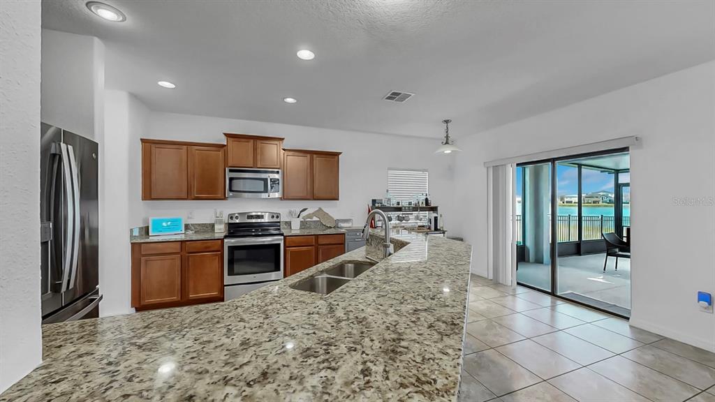 10012 Newminster Loop Ruskin, FL 33573 - Photo 16 of 59 a kitchen with stainless steel appliances granite countertop a refrigerator and a sink