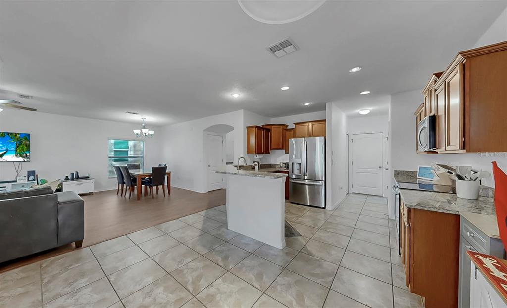 10012 Newminster Loop Ruskin, FL 33573 - Photo 17 of 59 a kitchen with stainless steel appliances kitchen island granite countertop a refrigerator a sink a dining table and chairs