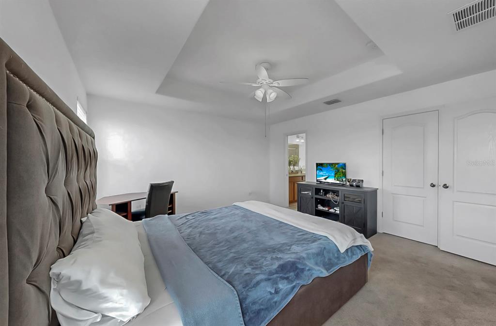 10012 Newminster Loop Ruskin, FL 33573 - Photo 27 of 59 a bedroom with a bed and a chandelier