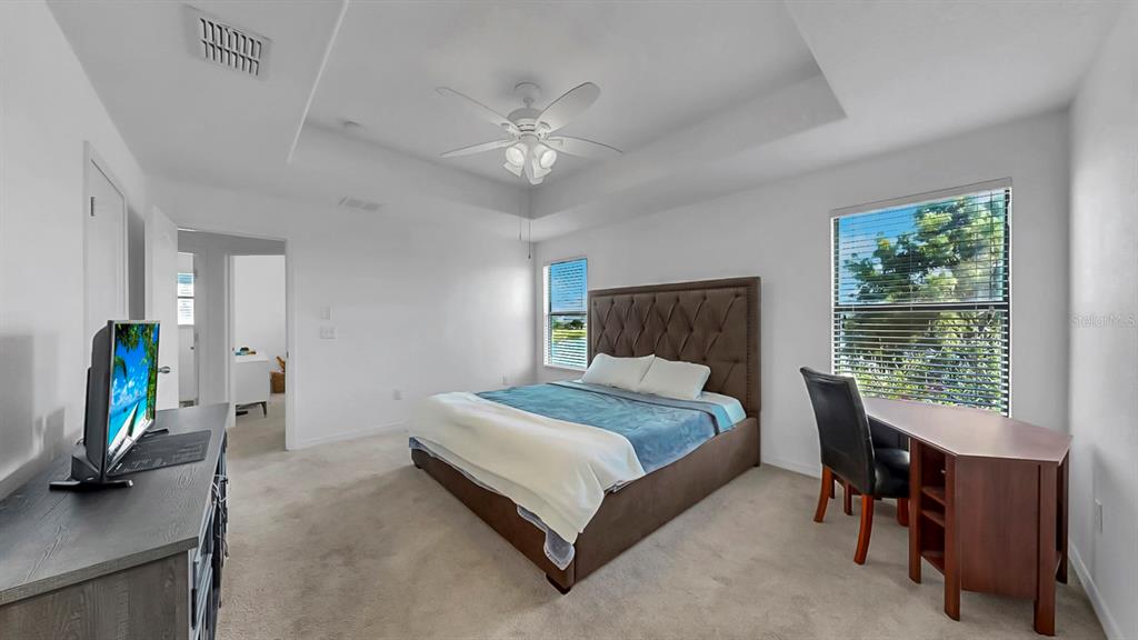 10012 Newminster Loop Ruskin, FL 33573 - Photo 28 of 59 a bedroom with a bed and a flat tv screen on dresser