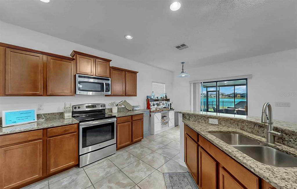 10012 Newminster Loop Ruskin, FL 33573 - Photo 6 of 59 a kitchen with stainless steel appliances granite countertop a sink stove microwave and refrigerator