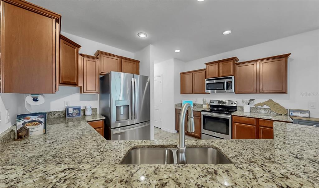 10012 Newminster Loop Ruskin, FL 33573 - Photo 7 of 59 a kitchen with stainless steel appliances granite countertop a sink refrigerator and microwave