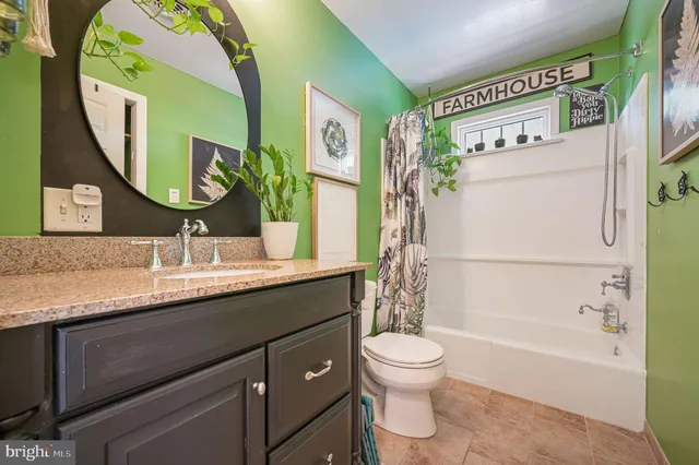 a bathroom with a granite countertop toilet sink and mirror