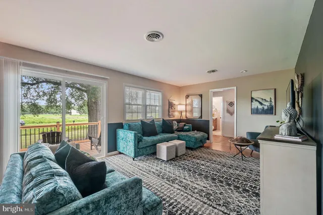 a living room with furniture floor to ceiling window and a flat screen tv
