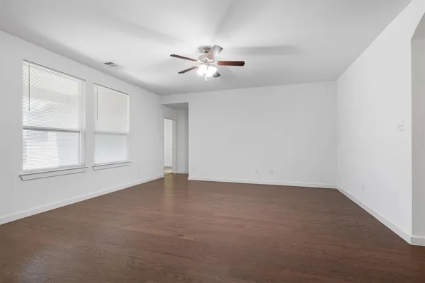 an empty room with chandelier fan and windows