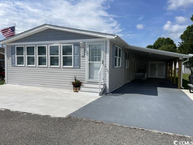 469 Sandpebble Surfside Beach, SC 29575 - Photo 1 of 39 Manufactured / mobile home with an attached carport, entry steps, and asphalt driveway