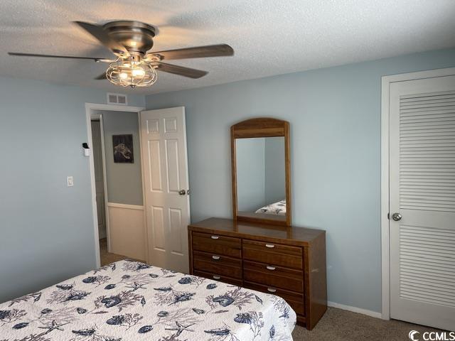 469 Sandpebble Surfside Beach, SC 29575 - Photo 27 of 39 Bedroom with carpet floors, ceiling fan, a closet, and a textured ceiling