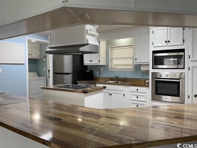 469 Sandpebble Surfside Beach, SC 29575 - Photo 4 of 39 Kitchen featuring appliances with stainless steel finishes, washer / dryer, white cabinetry, range hood, and butcher block counters