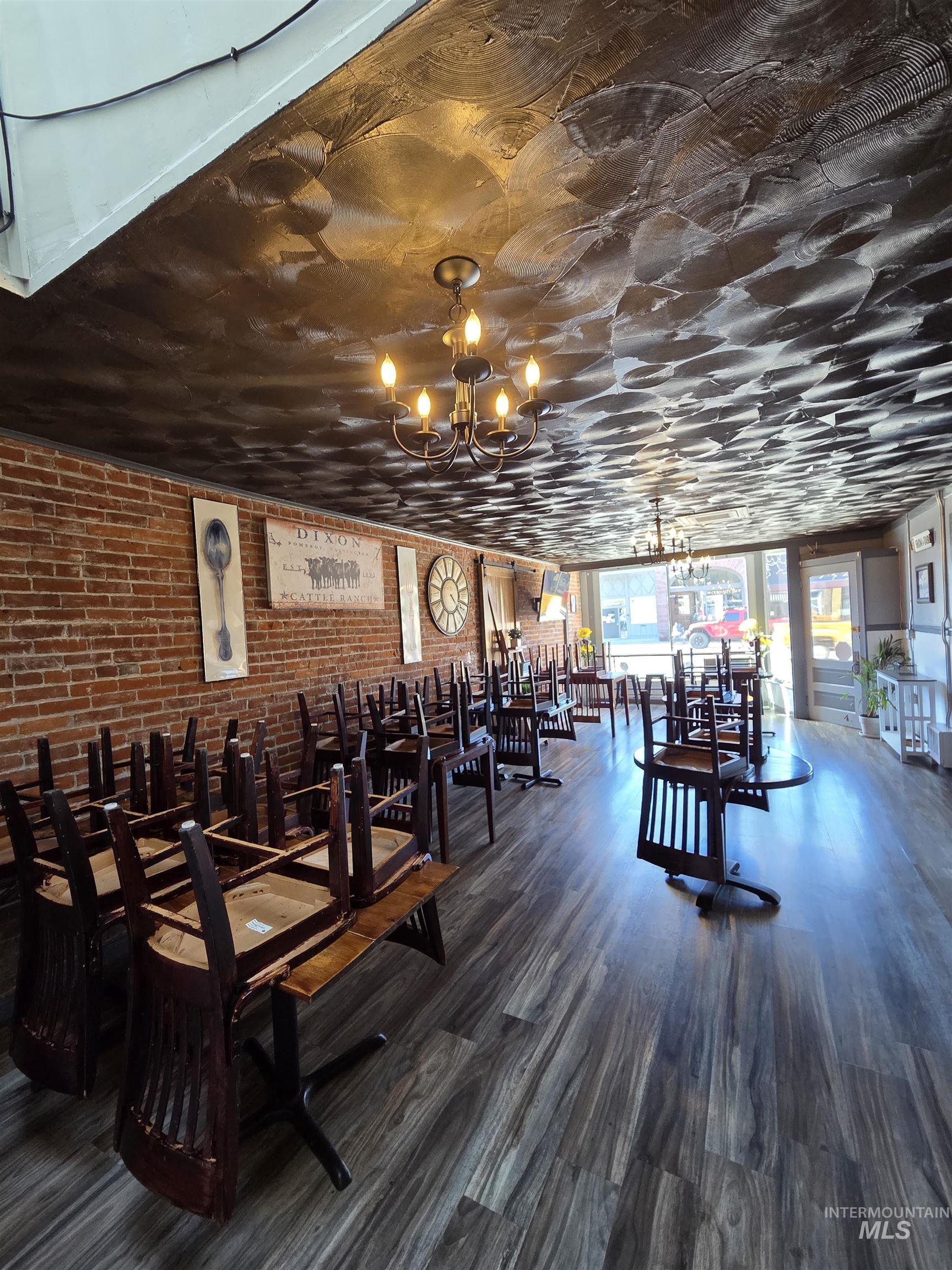Exposed brick accent wall and wood-finish flooring complement a pressed tin-style ceiling