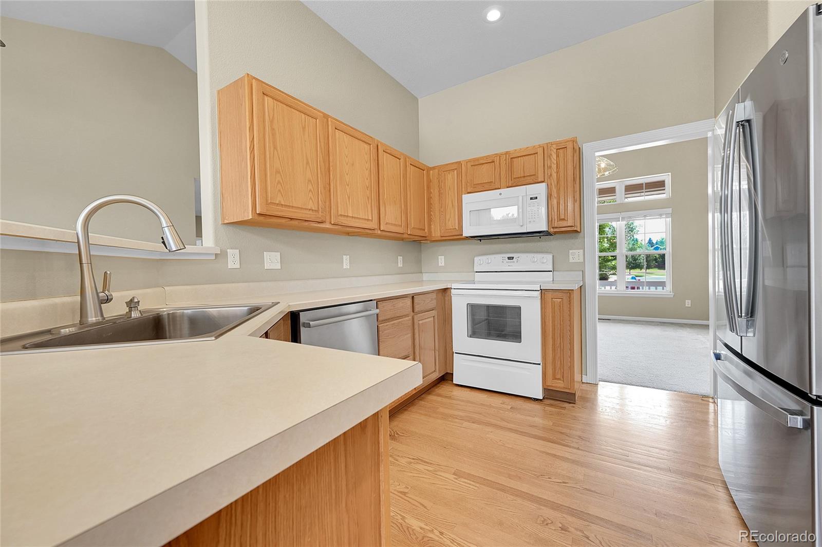 19115 East Belleview Place Centennial, CO 80015 - Photo 19 of 47 a kitchen with stainless steel appliances granite countertop a sink a stove top oven and wooden floors