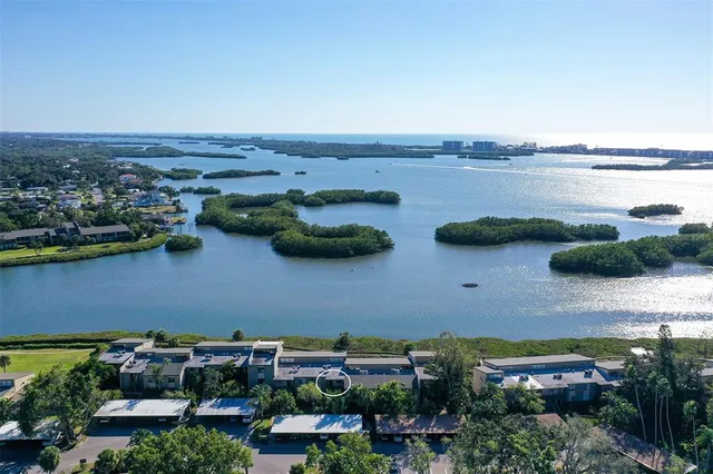an aerial view of a city with lots of residential buildings ocean and mountain view in back