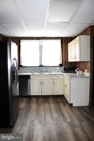 a kitchen with stainless steel appliances granite countertop a refrigerator a sink dishwasher a stove and white countertops with wooden floor