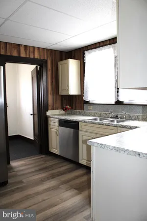a view of a kitchen with a sink and dishwasher with wooden floor
