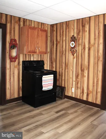 a view of a refrigerator in kitchen and an empty room with wooden floor