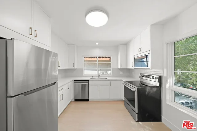 a kitchen with stainless steel appliances granite countertop a refrigerator a sink a stove and white cabinets