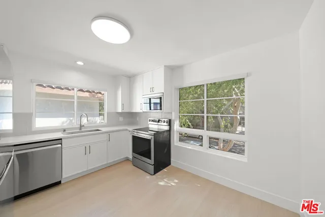 a large kitchen with granite countertop a sink and stove top oven