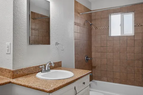 a bathroom with a granite countertop sink a mirror a shower and a bathtub