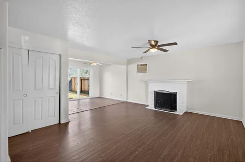a view of an empty room with wooden floor and a fireplace