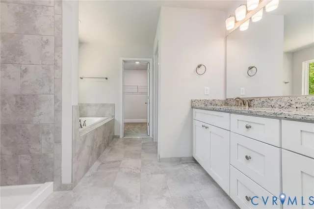 a bathroom with a granite countertop sink a mirror a bathtub and shower