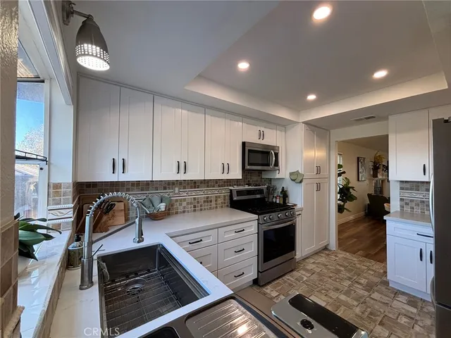 a kitchen with granite countertop a sink stainless steel appliances and cabinets