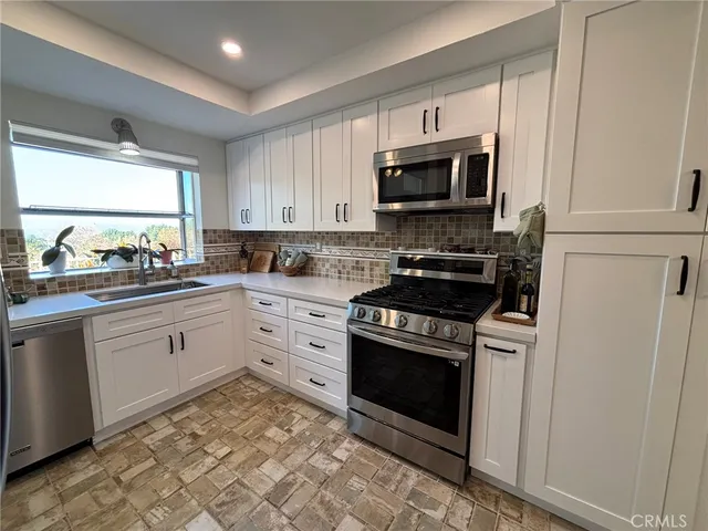 a kitchen with stainless steel appliances a stove a sink and a microwave