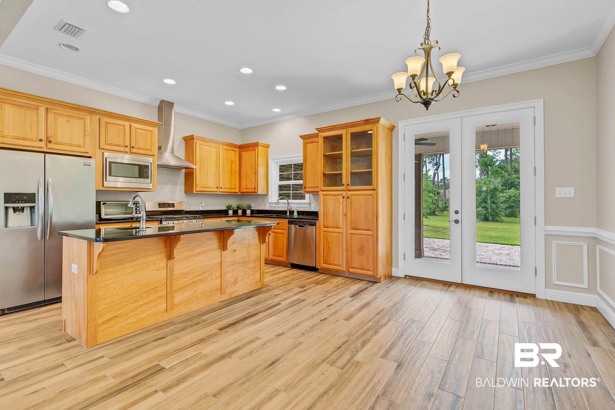 8145 Bay View Drive Foley, AL 36535 - Photo 13 of 81 Kitchen featuring stainless steel appliances, wall chimney exhaust hood, french doors, a breakfast bar, and dark countertops
