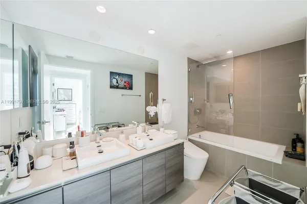 a bathroom with a double vanity sink toilet mirror and shower
