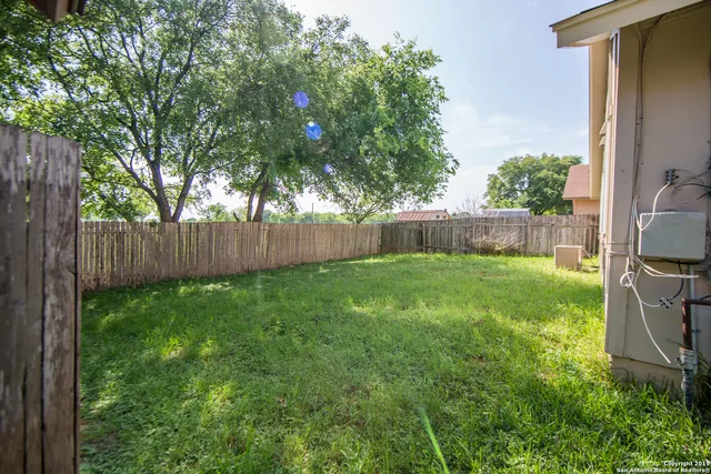 a view of backyard with wooden fence and large trees