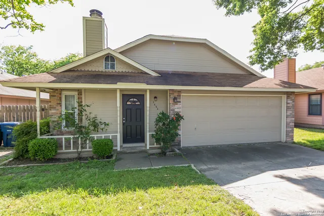 a front view of a house with a yard and potted plants