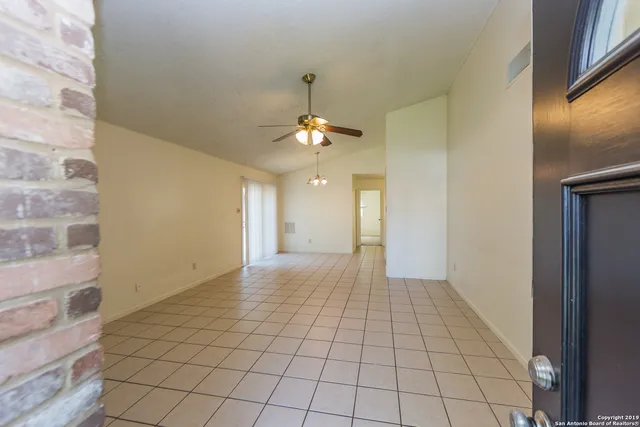 a view of an empty room and chandelier fan