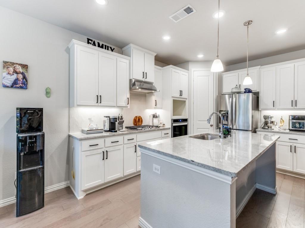 1608 Carnation Street Prosper, TX 75078 - Photo 11 of 25 a large kitchen with stainless steel appliances kitchen island a stove a sink dishwasher and a refrigerator with wooden floor