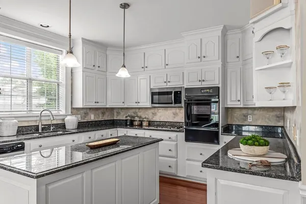 a kitchen with stainless steel appliances a refrigerator a stove top oven and a dining table with wooden floor