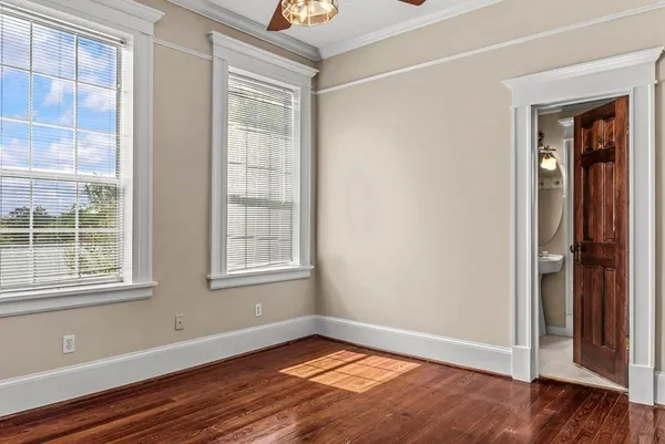 an empty room with wooden floor cabinet and windows