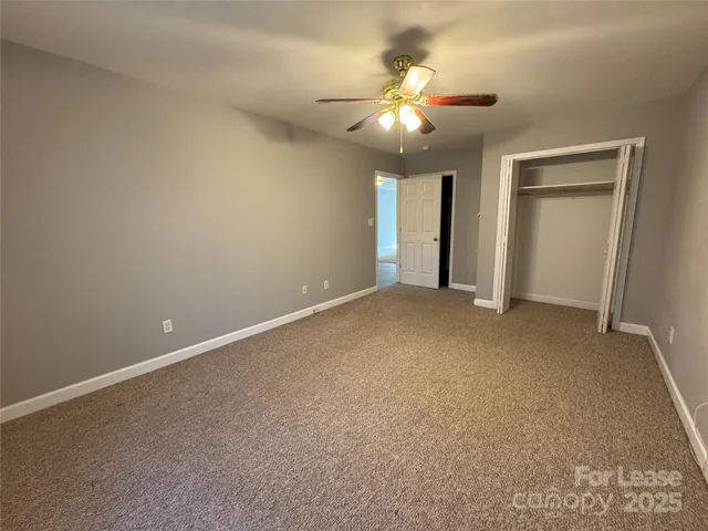 a view of an empty room with a chandelier fan