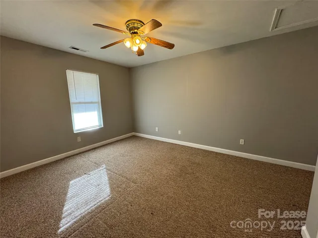 an empty room with a chandelier fan and a window