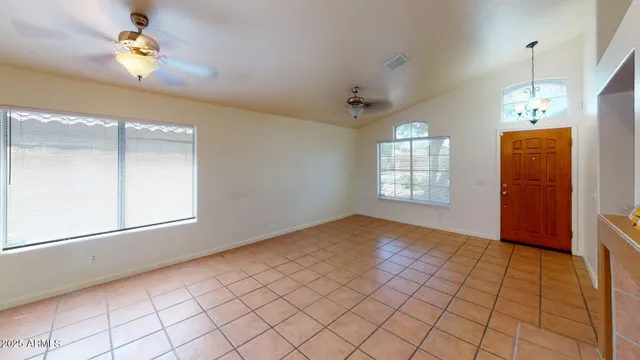 an empty room with windows and ceiling fan