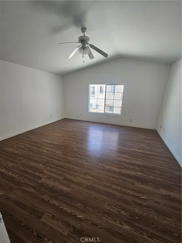 an empty room with wooden floor chandelier fan and windows