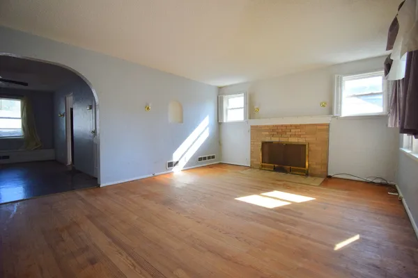 a view of empty room with wooden floor and fireplace