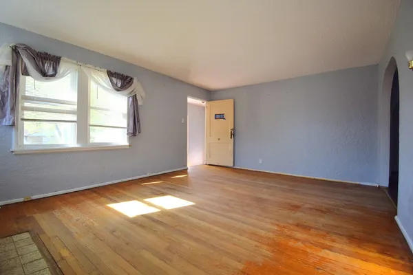 a view of an empty room with wooden floor and a window