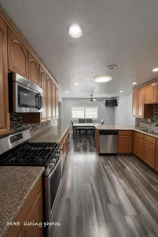 a kitchen with stainless steel appliances kitchen island granite countertop a stove a sink dishwasher and a microwave oven with wooden floor