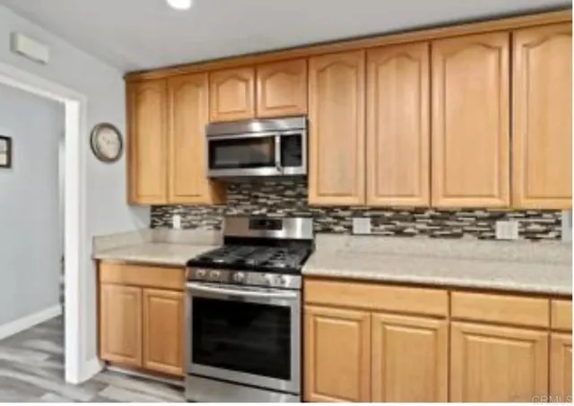 a kitchen with granite countertop stainless steel appliances a stove a microwave and cabinets