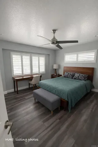 a spacious bedroom with a bed a chandelier and windows