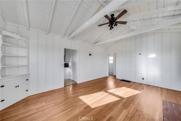 a view of empty room with wooden floor and ceiling fan