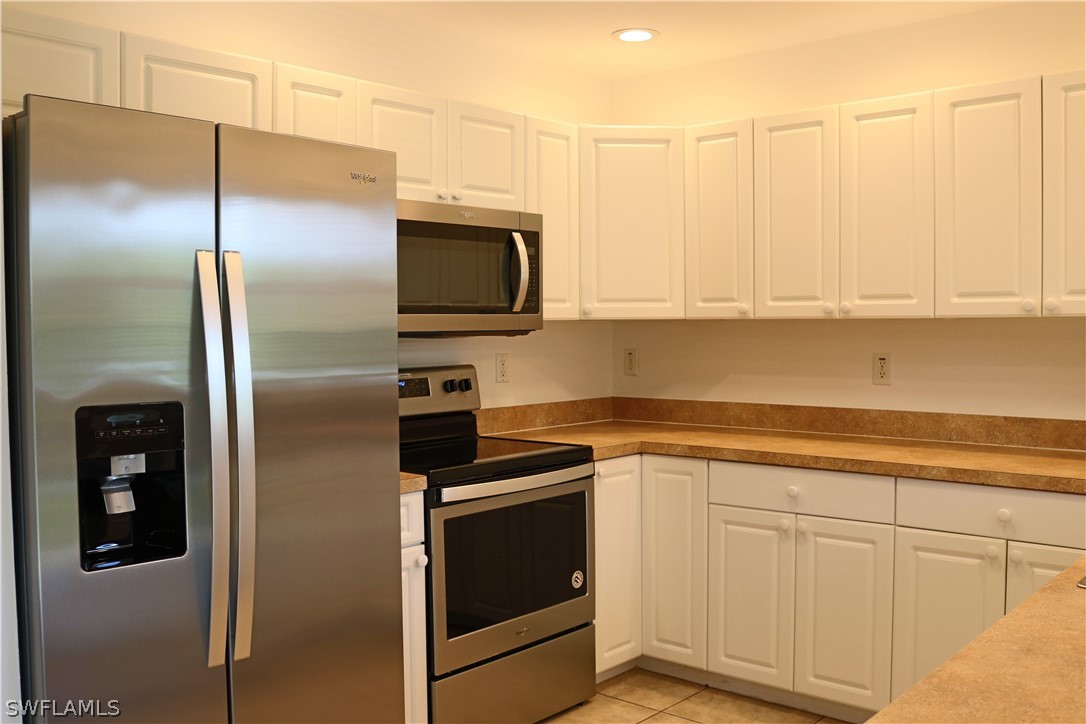 18425 Iris Road Fort Myers, FL 33967 - Photo 5 of 27 a kitchen with stainless steel appliances white cabinets and a refrigerator