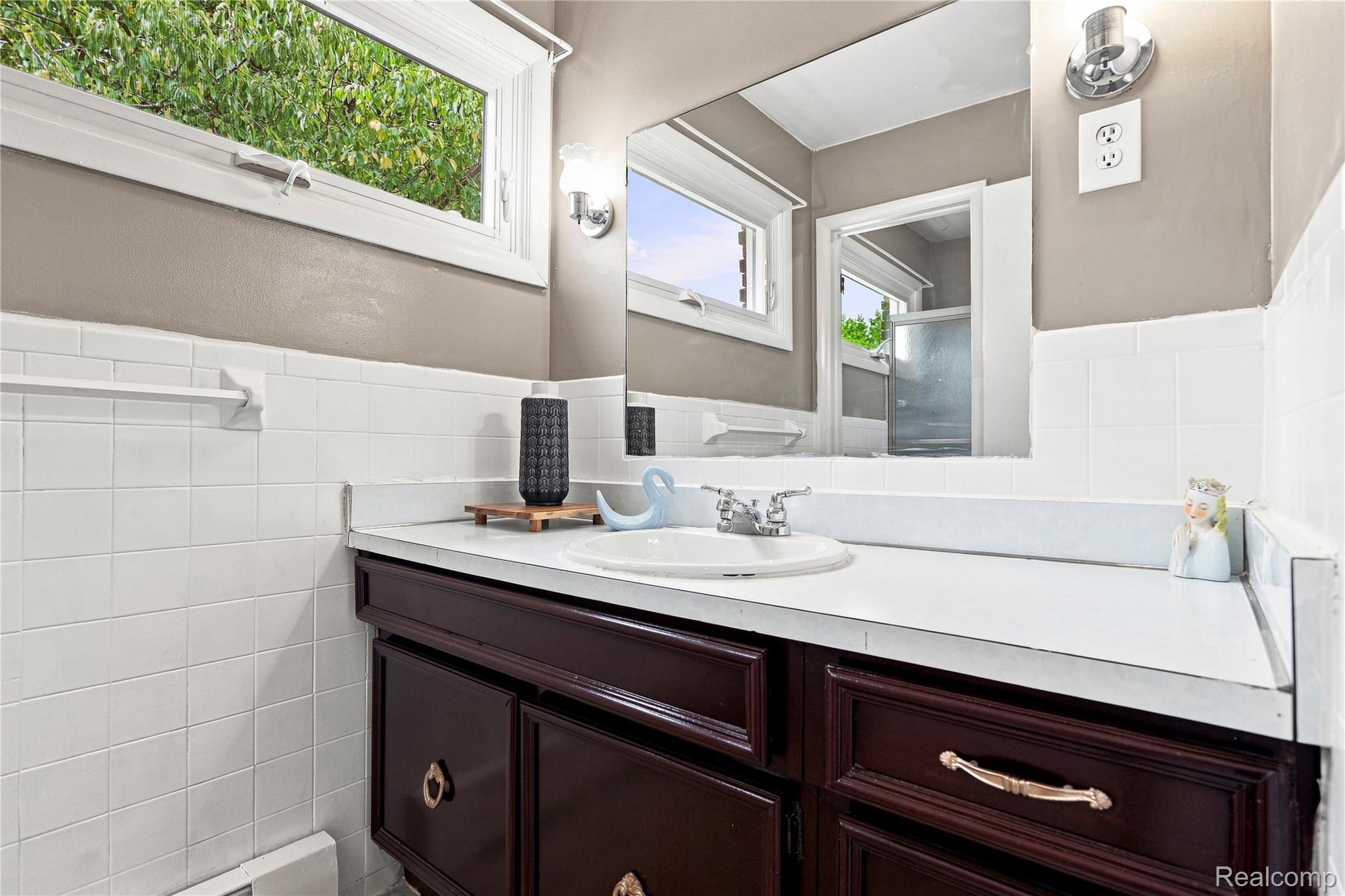 7386 Dean Road Fenton, MI 48430 - Photo 19 of 64 Bathroom vanity with integrated sink, dark wood-finish cabinetry, and white tiled walls
