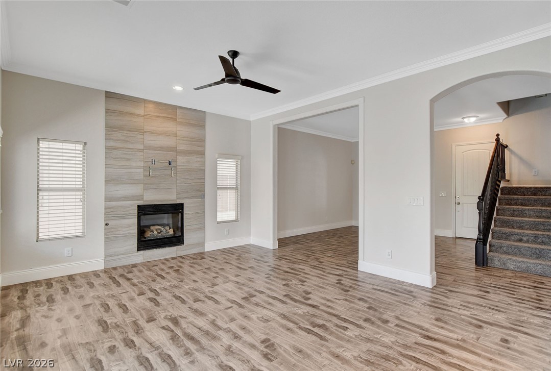 191 Verde Ridge Court Henderson, NV 89012 - Photo 10 of 36 Unfurnished living room with wood finished floors, ceiling fan, stairs, baseboards, and a fireplace