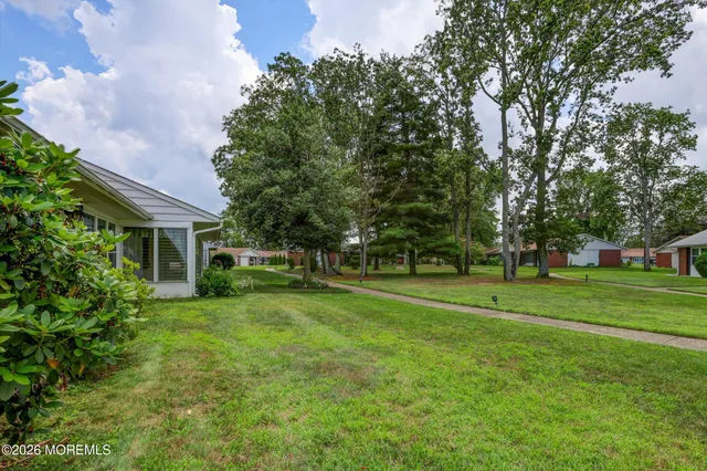 a view of a house next to a big yard and large trees