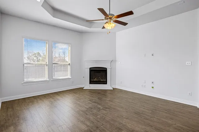 an empty room with wooden floor fireplace and windows